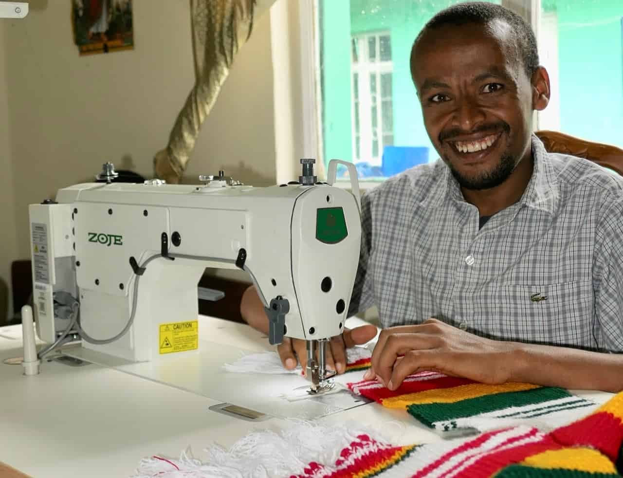 Bires Gashu smiling with his sewing machine.
