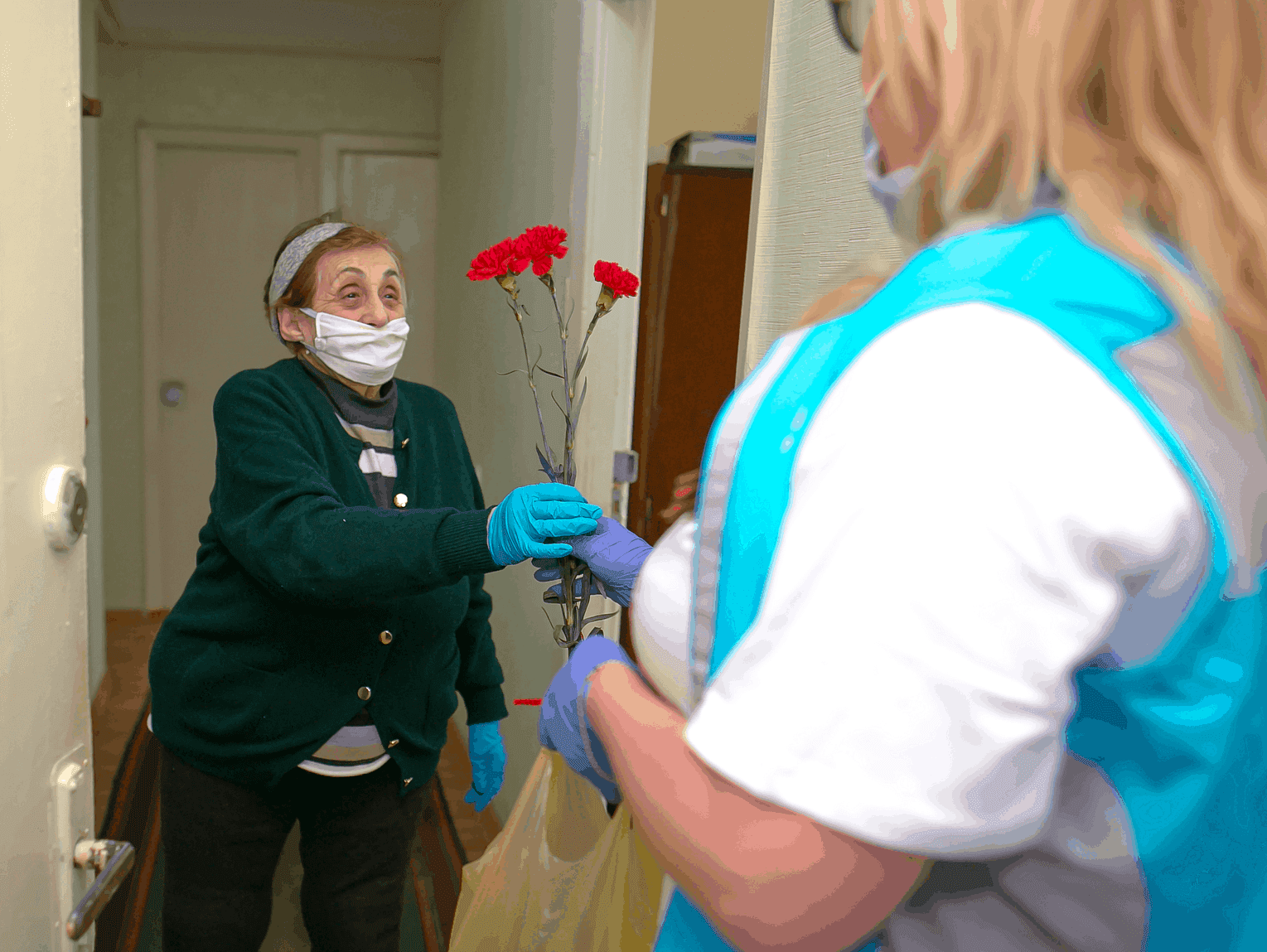 During the Coronavirus pandemic, a JDC homecare worker safely delivers a flower to a client, as well as food and medicine.
