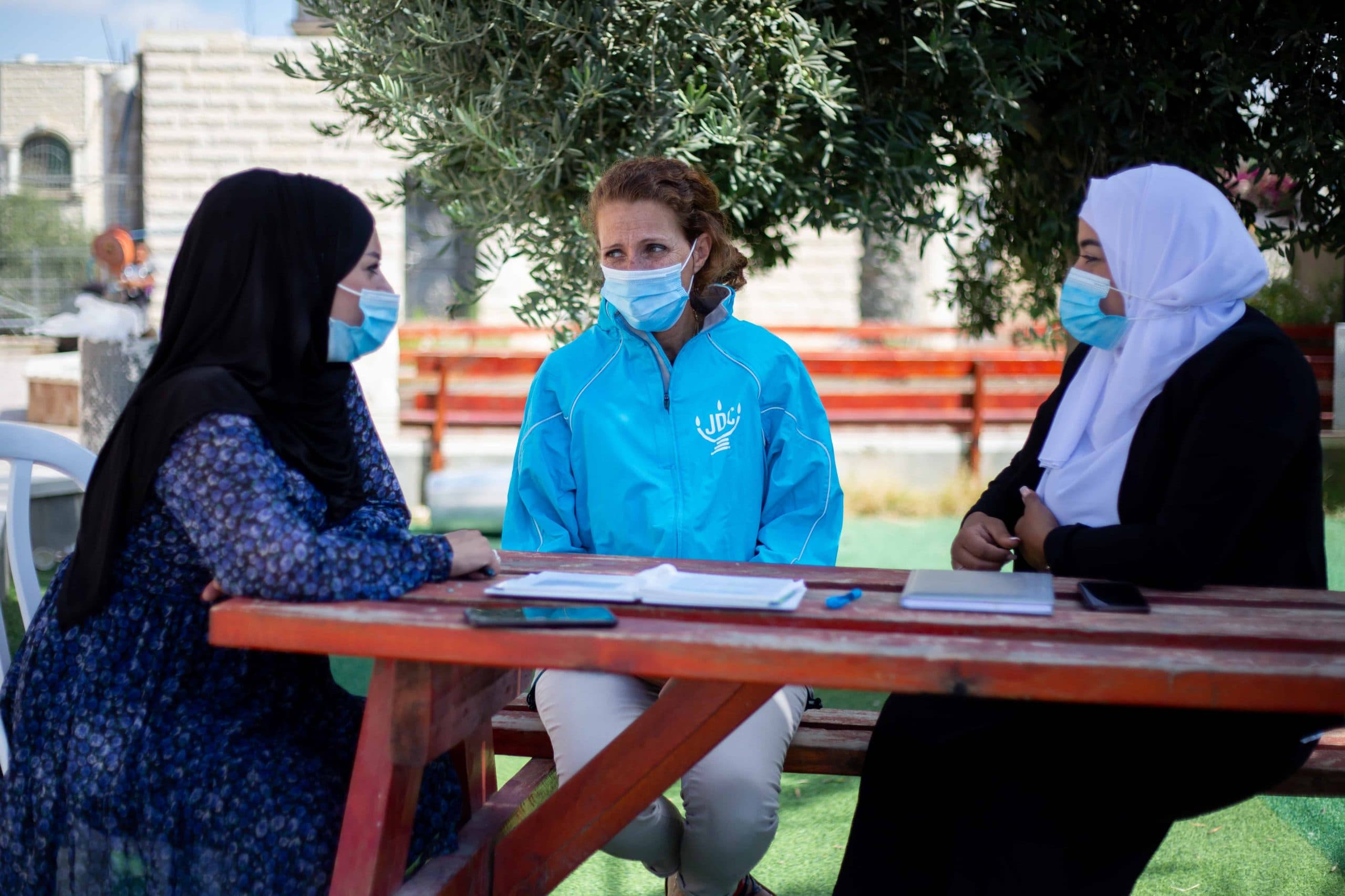 Ziva sits with two Arab Israeli, helping them with employment plans.