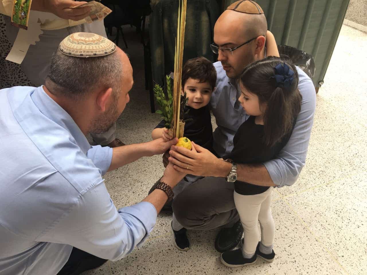 Rabbi Ari Oliszewski teaches congregants how to shake the lulav and etrog on Sukkot.
