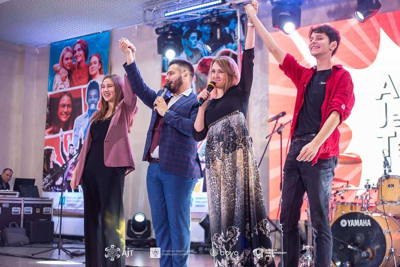 Irina Kozak and Leonid Rud stand with AJT leaders, raising their hands in victory after winning the AJT co-president election.
